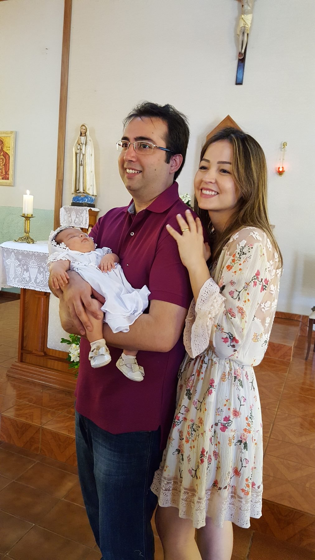 Os dois na igreja segurando um bebê no batizado