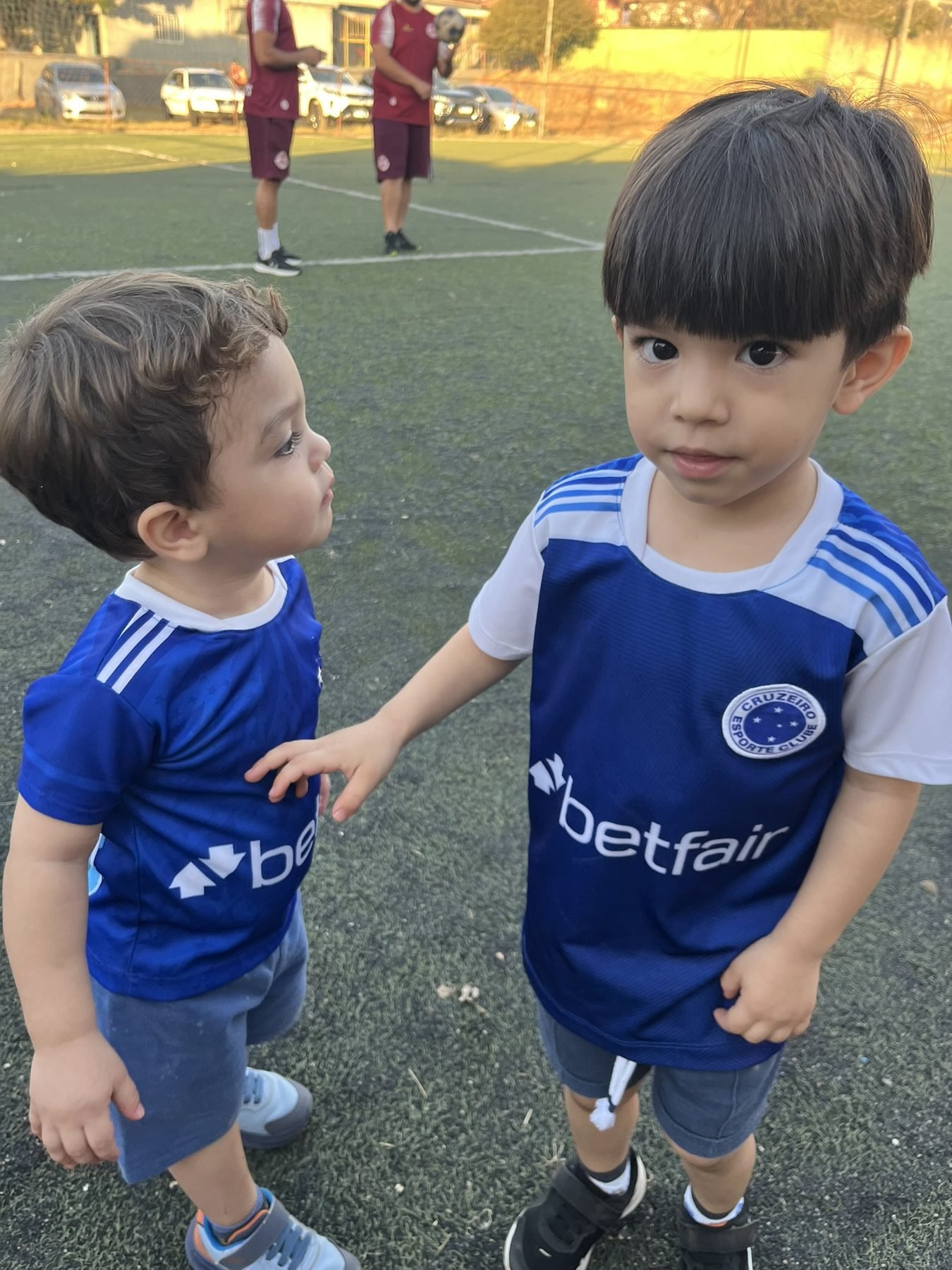 Pedro e Davi com camisas do Cruzeiro em um campo de futebol